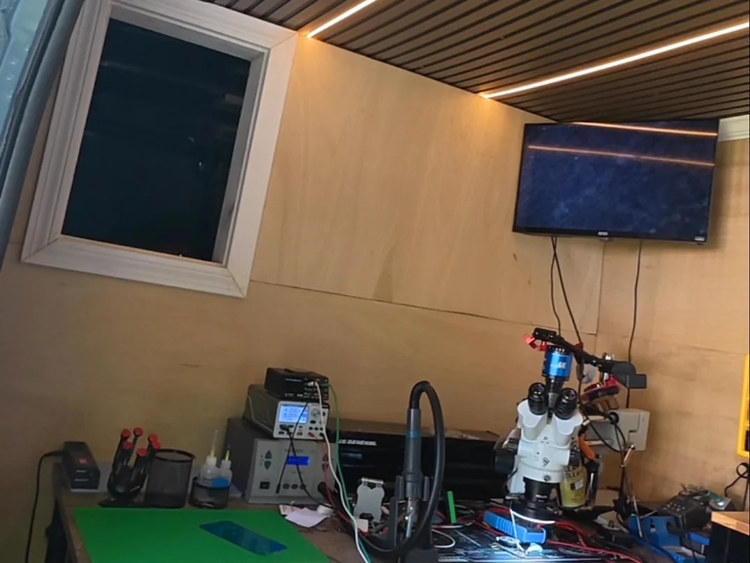 Inside the TEC CENTER van: a lit workbench with a stereo microscope, bench power supplies and a green anti-static mat